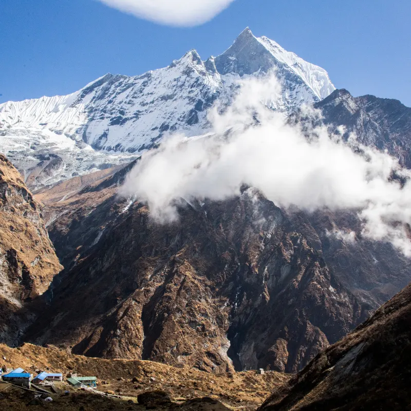 Iconic fishtail peak of Mount Machhapuchhre rising above alpine tea houses in the Annapurna trekking region.