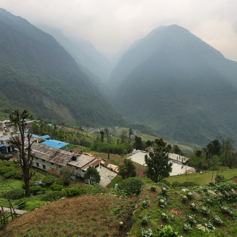 Misty view over a Himalayan mountain valley with a small trekking village in the Annapurna region of Nepal.