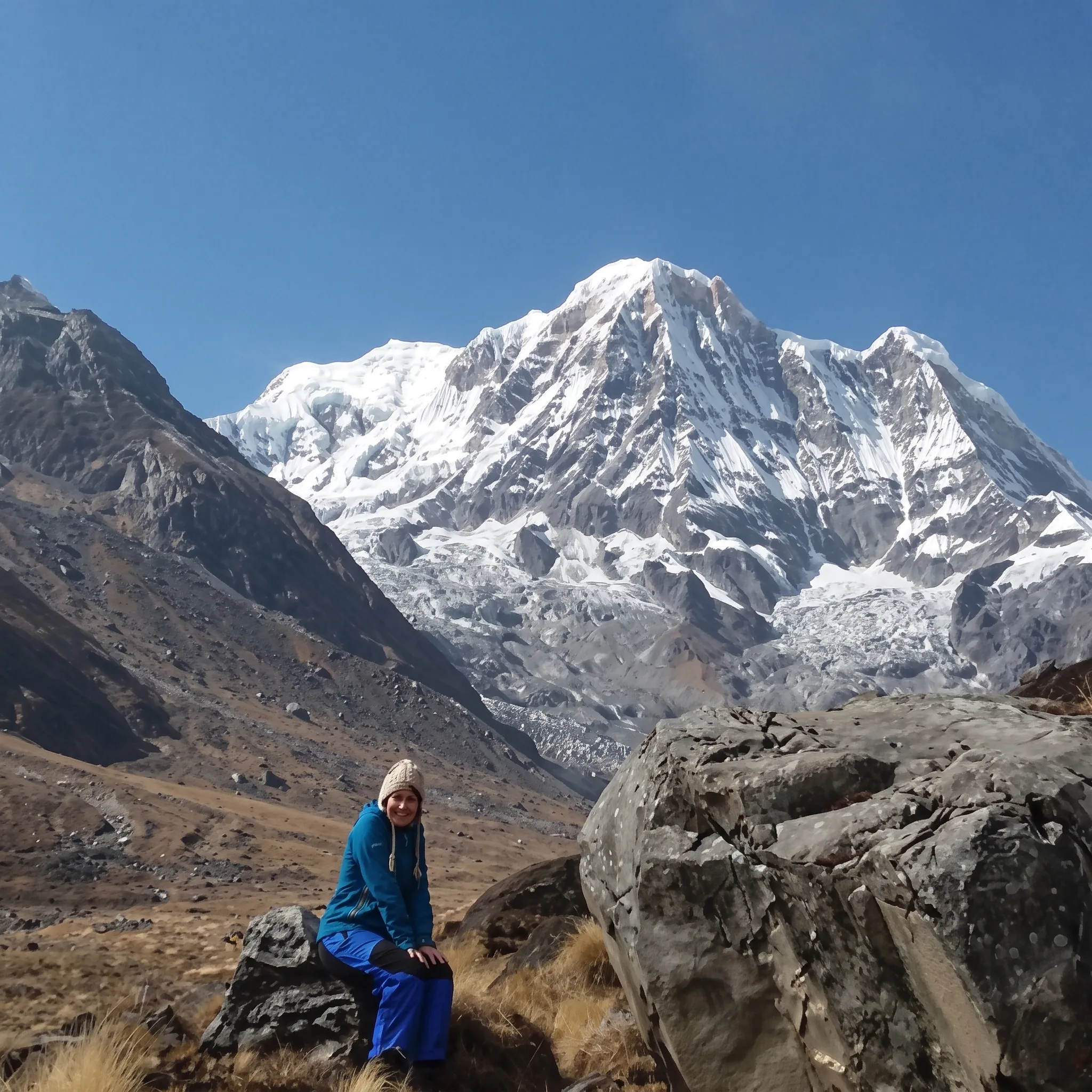 Hiker resting beside large boulders in a high mountain valley on the Jomsom Muktinath and Ghorepani Poon Hill trek.