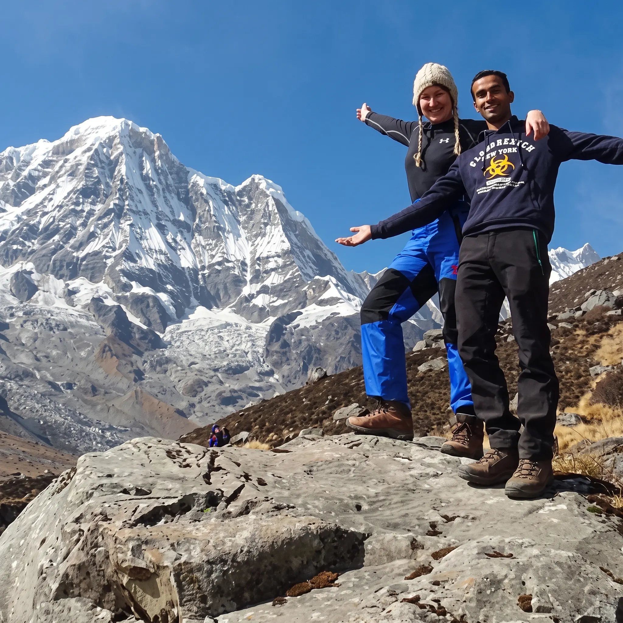 Two trekkers posing on a rocky outcrop with snow-capped Himalayan peaks on the Jomsom Muktinath and Ghorepani Poon Hill Trekking route.
