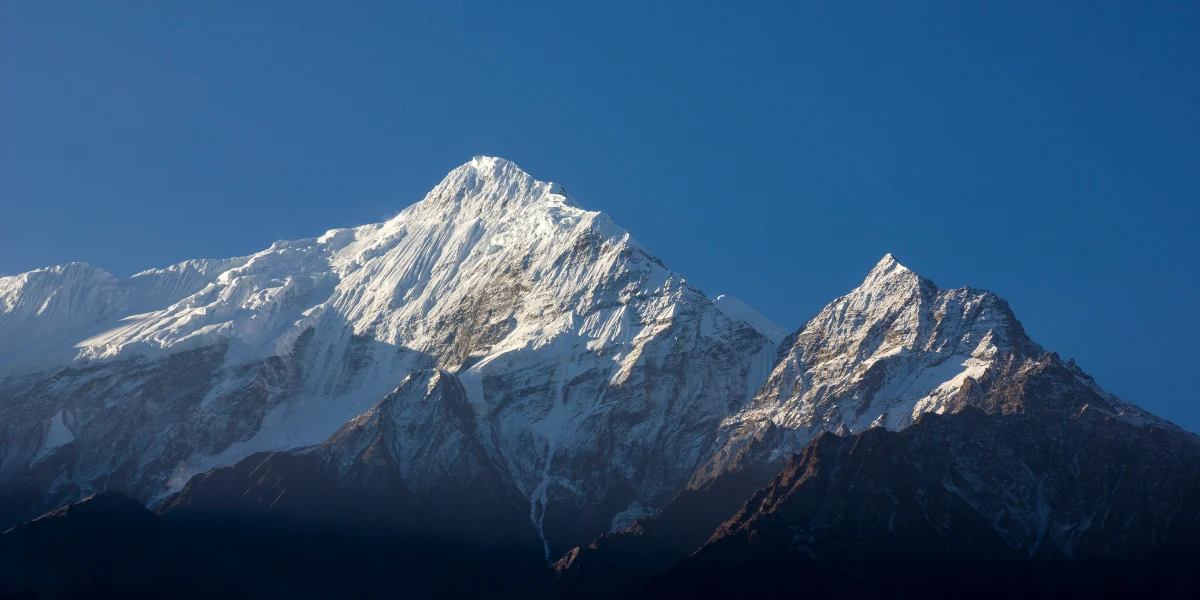 Snow-capped peaks of the Nilgiri Himal mountain range against a clear deep blue sky in Nepal.